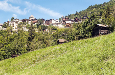 阳光明媚的一天，圣卢克山谷瑞士阿尔卑斯山草地上的木屋。