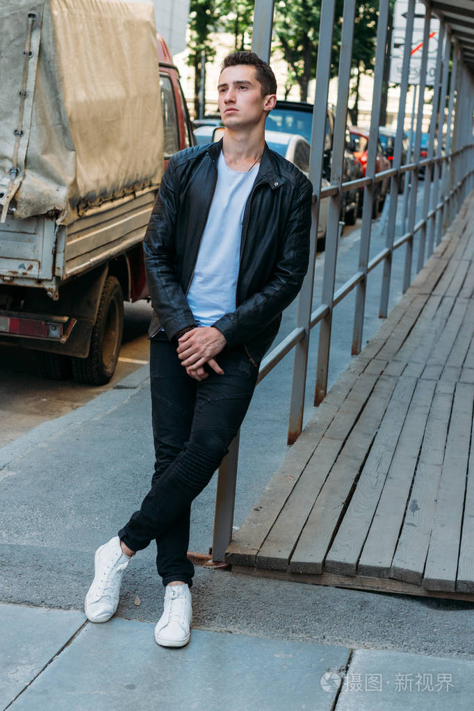 迷人的性感男人戴着太阳镜站在街上自信自负傲慢模特