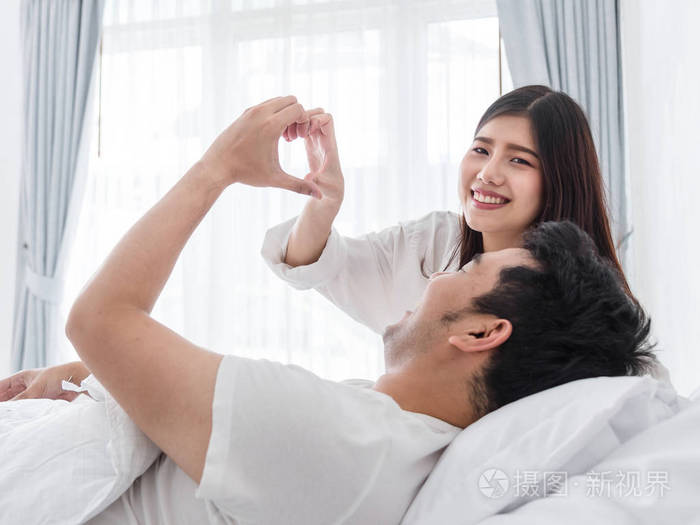 浪漫的情侣在床上用手爱标志生活方式的概念