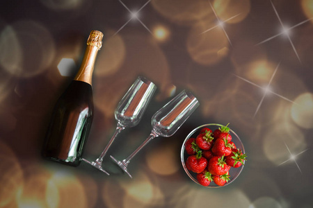 一瓶香槟和两个空杯子在水平的位置和一碗草莓