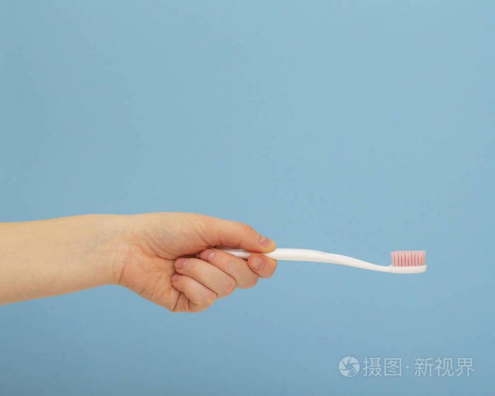 女人手拿白色牙刷蓝色背景