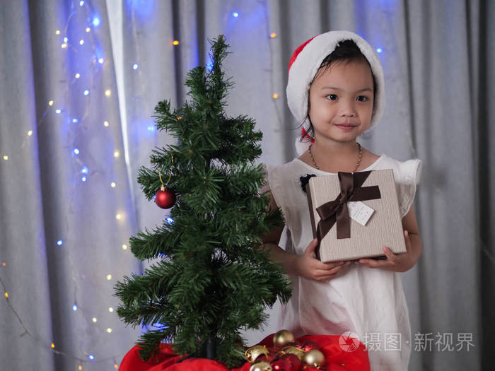快乐的亚洲女孩，带着圣诞老人的帽子，在家里。