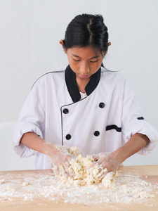 快乐的亚洲女孩在统一准备面粉饼干或比萨饼面团的生活方式概念。