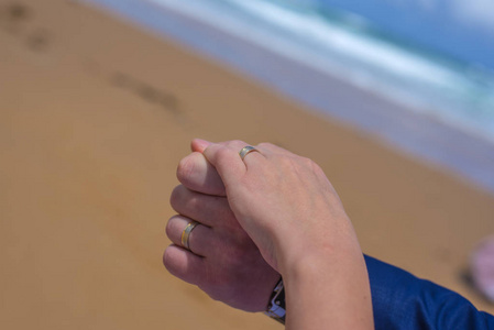 澳大利亚美丽的海滩上，刚结婚的一对手拿着戒指