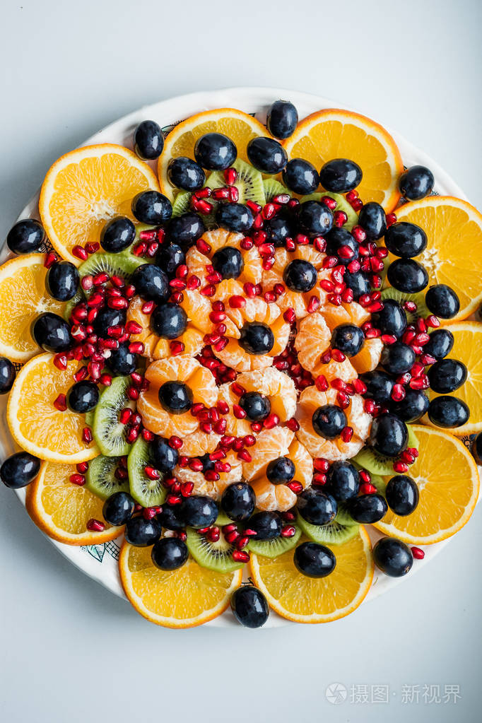 水果甜点。 水果切片。 白色盘子上的橙色石榴葡萄。 节日餐桌。
