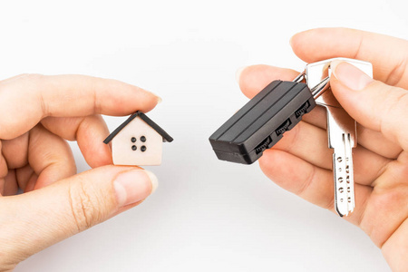 s hands hold keys with padlock and house symbol. The background 