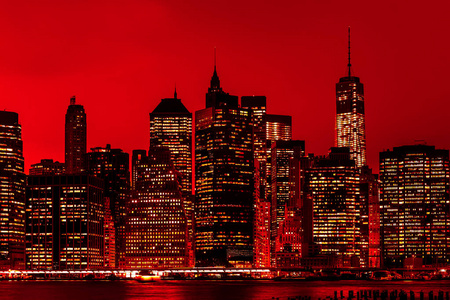 曼哈顿晚上有灯光和倒影。 纽约市天际线。 戏剧性的暗红色色调的图像