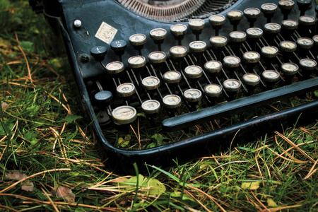 古老的黑色老式古董德国打字机在绿草上合上