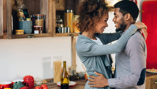 可爱的黑人夫妇拥抱在舒适的厨房