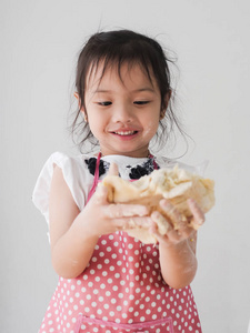 快乐的亚洲女孩与粉红色围裙准备面粉饼干或比萨饼面团的生活方式概念。