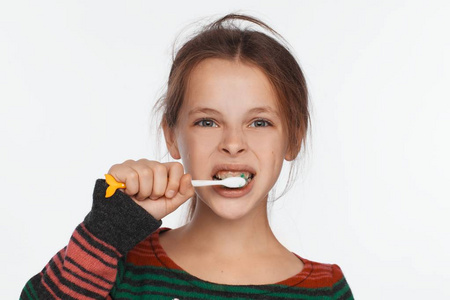 一个八岁的女孩用牙刷刷牙的肖像。 条纹毛衣