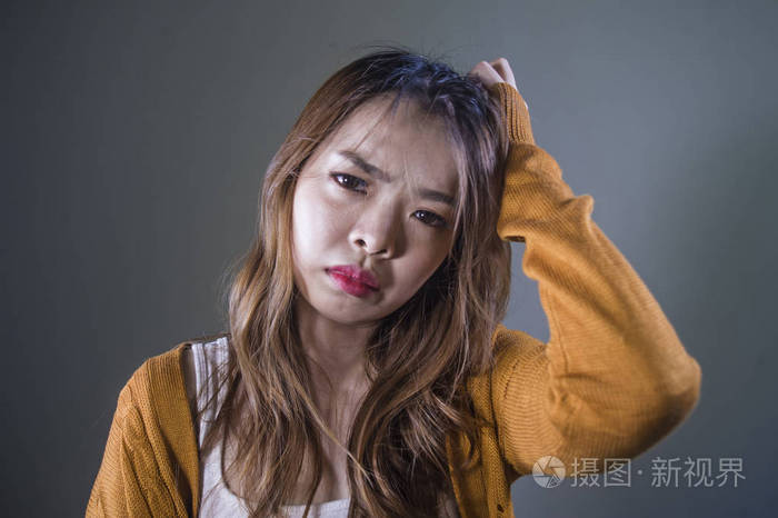 年轻的疯狂绝望悲伤的亚洲女性在孤独的黑暗背景下痛苦痛苦表情抑郁和
