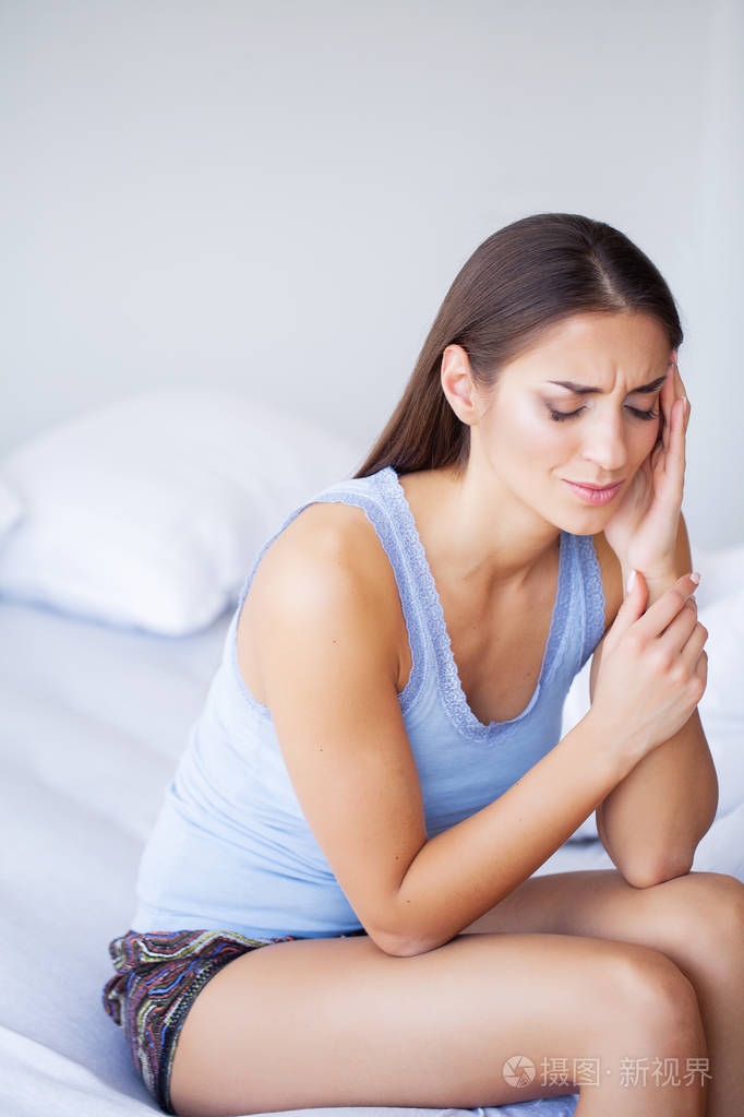 头部疼痛迷人的年轻女子在床上醒来看上去很不开心感觉很不舒服
