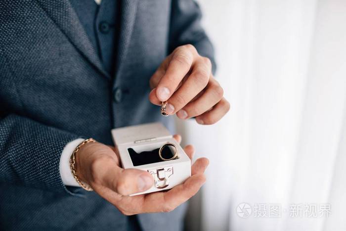 s hand holding engagement rings in box ,close up