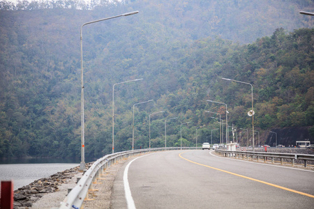 在水库坝沿线混凝土道路上行驶，区域内天然林树山环境丰富..自然旅游旅游生态旅游交通环境关注概念