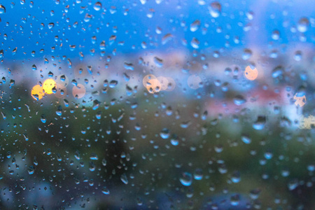 窗玻璃表面有模糊的城市景观背景的雨滴