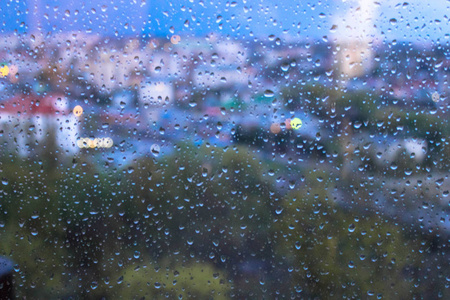 窗玻璃表面有模糊的城市景观背景的雨滴
