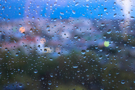 窗玻璃表面有模糊的城市景观背景的雨滴