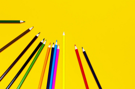 彩色铅笔在明亮的黄色背景上，俯视平面与复制空间。木制彩色铅笔供绘画，实物供创意，学习用品特写..回到学校的概念