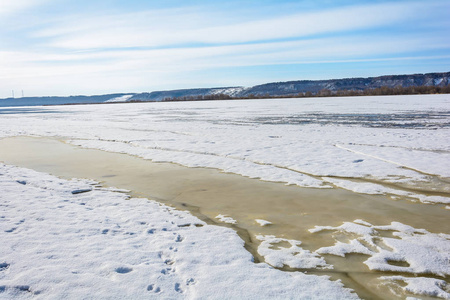 在温暖的春天阳光的影响下，河上厚厚的冰裂成了碎片