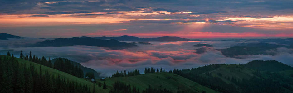 全景照片山脉通过早晨五颜六色的雾在夏天。 美丽的日出在喀尔巴阡山，可见的轮廓和粉红色的云在阳光下。