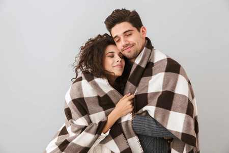 一对可爱的夫妇，一对一对裹在毯子里的男人和女人，微笑着拥抱在一起，在灰色的背景下孤立地拥抱在一起