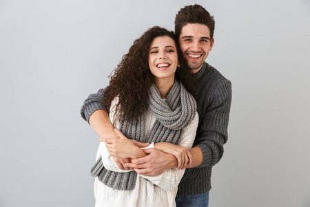 一对可爱的夫妇的肖像，男人和女人微笑着，拥抱在一起，被孤立在灰色的背景上