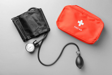 灰色背景下的血压计和急救箱。医疗保健理念
