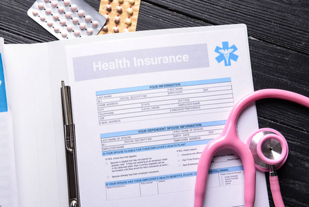 医疗保险表格听诊器和药片在诊所的桌子上