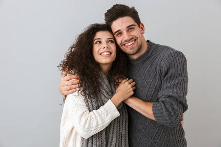 一对幸福的夫妻的肖像，男人和女人微笑着，拥抱在一起，被孤立在灰色的背景上