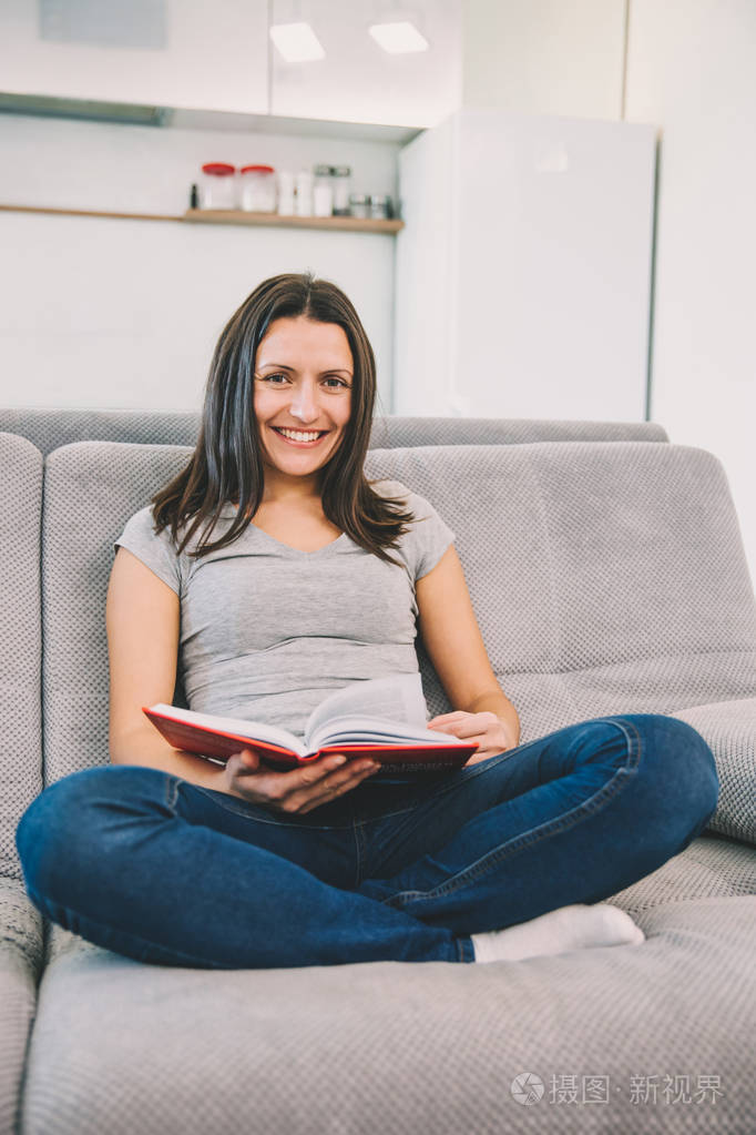 坐在沙发上的女人拿着一本书