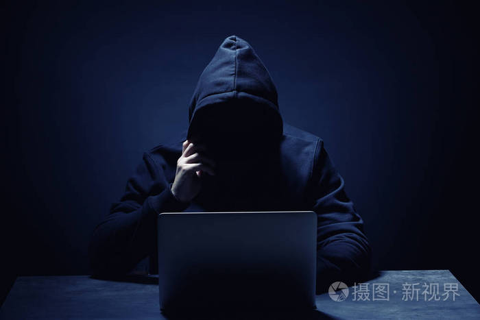 专业黑客笔记本电脑坐在黑暗背景的桌子上