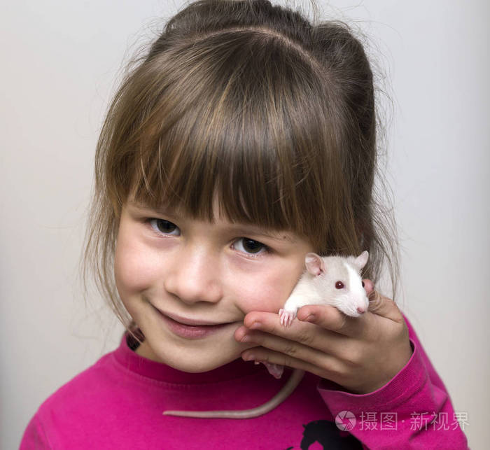 快乐微笑可爱的儿童女孩的肖像与白色宠物老鼠仓鼠在轻拷贝空间背景养