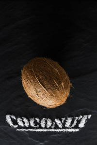 整个成熟的椰子在黑色的纹理背景上，靠近和俯视