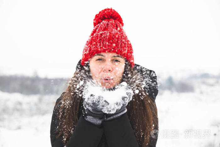 微笑的女人戴着红帽子，手里拿着雪