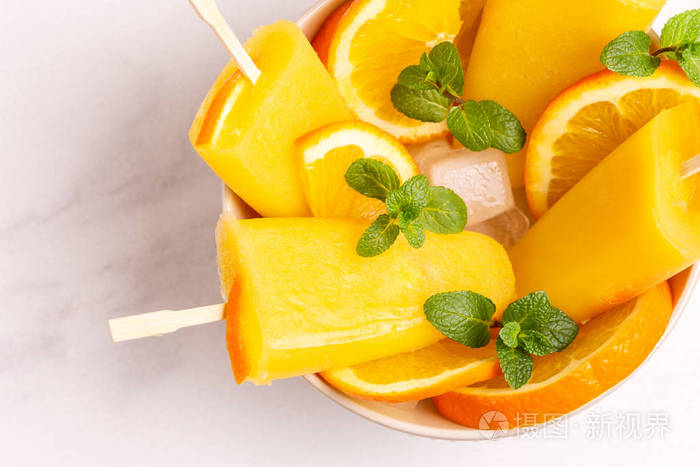 自制橙色冰棒成熟橙色和新鲜薄荷在轻大理石背景健康的