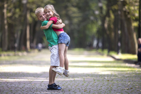 关系阳光两个可爱的年轻滑稽的微笑的孩子,女孩和男孩,哥哥抱着妹妹在