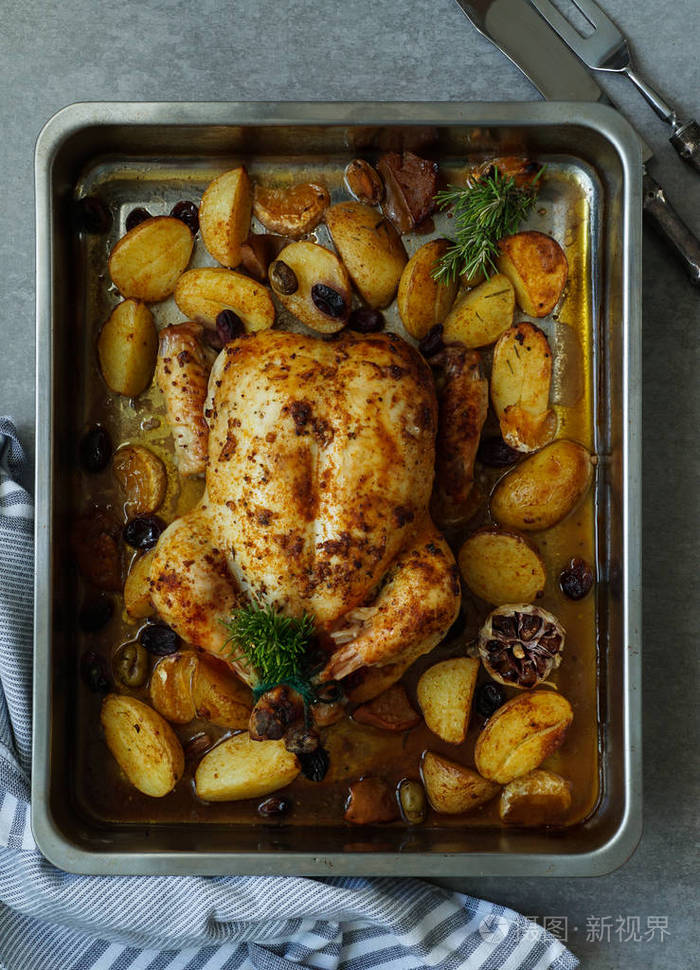 烤火鸡或多汁的鸡肉有金黄的皮肤有葡萄和土豆橘子烤盘中的烤鸡圣诞