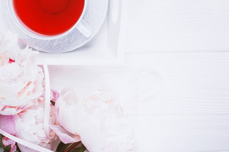 白色木制背景上的粉红色水果茶和花牡丹。 顶部视图复制空间