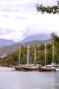 观船和美丽的山脉在菲蒂耶土耳其日出。 五彩缤纷的风景，船在蔚蓝的大海，青山。