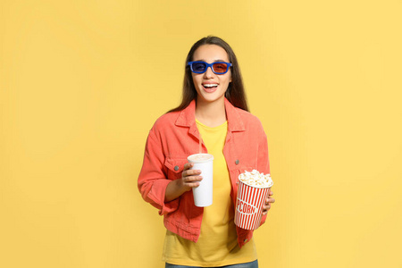 在彩色背景电影放映期间带3D眼镜爆米花和饮料的妇女