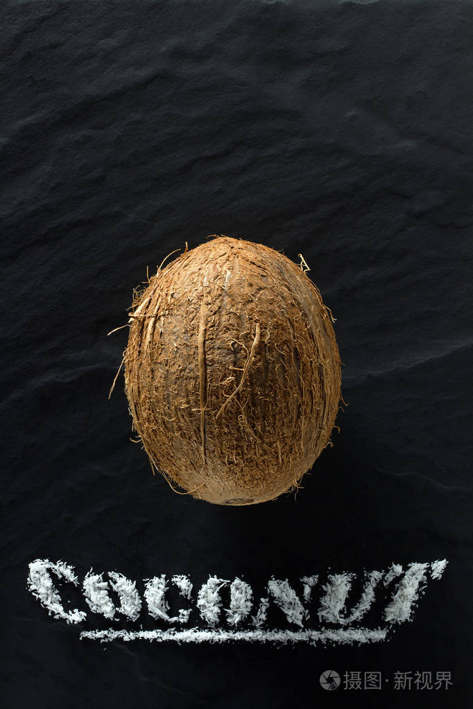 整个成熟的椰子在黑色的纹理背景上靠近和俯视