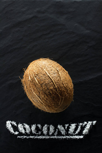 整个成熟的椰子在黑色的纹理背景上，靠近和俯视