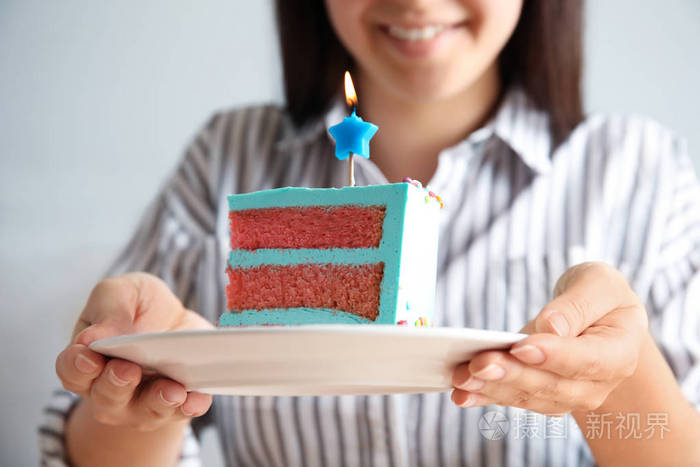 女人拿着新鲜可口的生日蛋糕,拿着蜡烛,特写