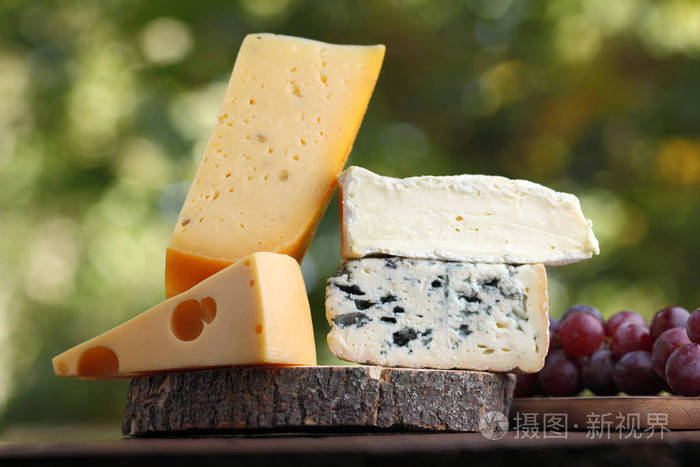 各种奶酪和葡萄片在模糊的背景上. 在木板上涂上dorblu和软奶酪.
