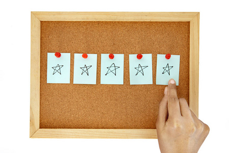 在软木钉板上用一张纸条，上面有五星级的手绘图案，象征着优秀的顾客满意度，反馈观念隔离在白色上