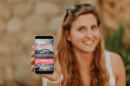 可爱的金发女人手里拿着手机，屏幕上有旅行社网站。