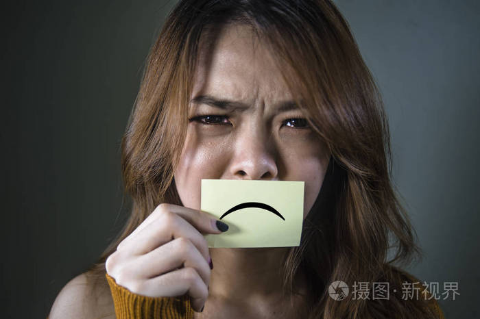 年轻的,不知所措和沮丧的亚洲学生女孩拿着纸,悲伤