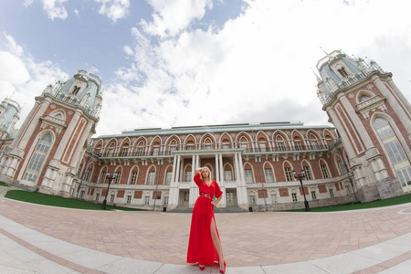 美丽而优雅的女孩穿着一件红色的长裙站在中世纪城堡的中央