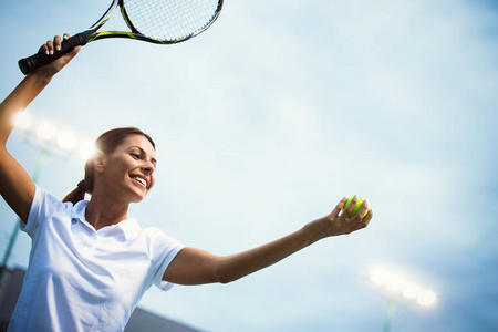 在网球比赛中，女运动员微笑着拿着球拍